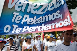 Credit: Flickr, Riccardo Vásquez. Opposition activists hold signs saying they will fight for Venezuela rather than lose their country, as mediation talks begin.
